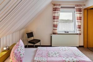 a bedroom with a bed and a chair and a window at Ferienwohnung Karin in Marienhafe
