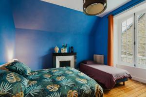 a blue bedroom with a bed and a fireplace at Villa La Côte du Chat in Hédé