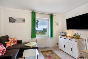 Una sala de estar con un sofá y un televisor. en Bäckerhus - Ferienwohnung 6, en Wiek auf Rügen