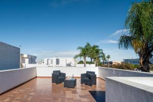 a balcony with black chairs and palm trees at Villetta Panoramic Rooftop San Foca in San Foca