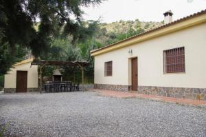 un edificio con una mesa y un pabellón al lado en Rural Montes Málaga: Finca Pedregales, en Málaga