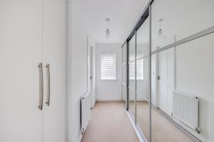 a corridor of a room with white walls and mirrors at Stunning Detached House with Driveway Parking, Office Room, Self-Check-In, Fast WiFi and Smart TV with Sky and Netflix by Yoko Property in Milton Keynes