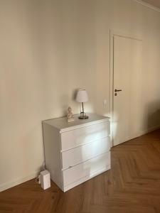 une commode blanche avec une lampe dessus dans l'établissement Brand new apartment in a historical location, à Riga 1 autre photo