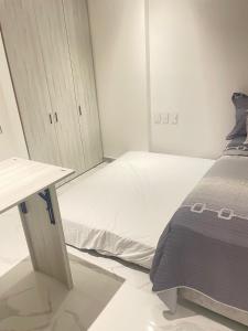 a small bedroom with a bed and a table at Sui Loft Apto 1311 in Santa Marta