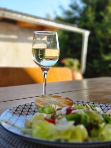 una copa de vino blanco junto a un plato de comida en Mały Domek, en Stara Kamienica