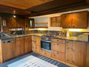 a kitchen with wooden cabinets and a stove top oven at Paradise View - 5 BR Gstaad Paradise View Chalet with Outdoor Jacuzzi in Rougemont