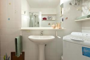 une salle de bains blanche avec un lavabo et un miroir dans l'établissement La Casa Al Mare, à Castelsardo 17 autres photos