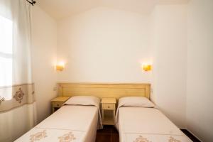 twee bedden in een kleine kamer met witte muren bij Borgo Degli Ulivi in Àrbatax +37 foto's