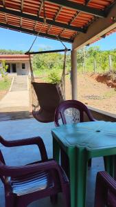 a green table and chairs under a porch with a hammock at CANTINHO DA ROSA ac - RIO PRIVATIVO in Manhã +15 photos