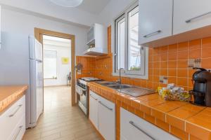 cocina de azulejos de color naranja con fregadero y fogones en Villa Marigù con spa e piscina, en Scicli