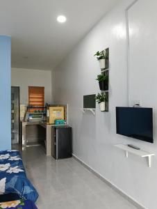 a room with a white wall with a flat screen tv at Roomstay NAZALÏA in Kijal