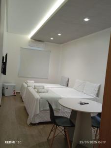 a white bedroom with a bed and a table at AS PLAZA HOTEL in Paranatama