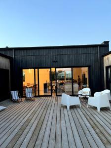 a deck with chairs and tables on a building at Villa Wax - Piscine et plage in Santec