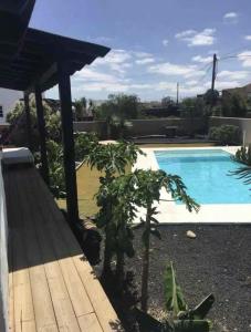 a garden with a swimming pool and a wooden deck at Villa Ballena in Lajares