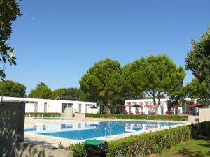 a large swimming pool with trees in the background at Parque de Campismo Orbitur Montargil in Montargil