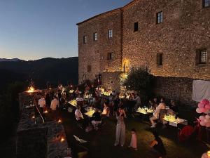 un groupe de personnes assises à des tables devant un bâtiment dans l'établissement TENUTA CASTEL DELL'AQUILA, à Gragnola