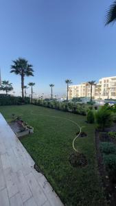 a park with palm trees and a hose on the grass at 3 bedroom apartment, Prestigia, Plage des Nations in Sidi Bouqnadel +9 photos