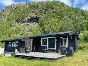a blue house with a porch in front of a mountain at Mountain Cabin With Magical View And Tranquil Lake in Matre