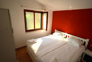 a bedroom with a white bed with a red wall at Adriatic Vacation House in Ližnjan
