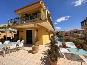 a patio with tables and chairs and a building at Appartamento Venere in villa 18pax in Marina di Ragusa