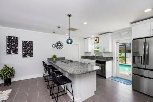 a kitchen with white walls and a large island with black chairs at Ocean Breeze by Sun Palace Vacations in Fort Myers Beach