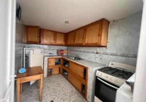 a small kitchen with wooden cabinets and a stove at Güicani Hostel in Güicán