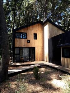 a small wooden house in the woods with a tree at Bosque Cipreses Sur in San Carlos de Bariloche