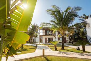 a building with palm trees in front of it at Hotel Vila Marola in Taíba