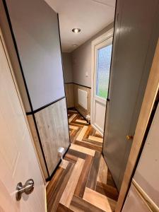 a hallway with a door and wooden floors and a window at Golden Sands Holiday Home in Skegness