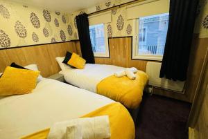 a hotel room with two beds and two windows at Golden Sands Holiday Home in Skegness