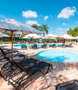 einen Pool mit Stühlen, Tischen und Sonnenschirmen in der Unterkunft Casa no Resort - Aguas de Santa Barbara in Águas de Santa Barbara + 17 Fotos