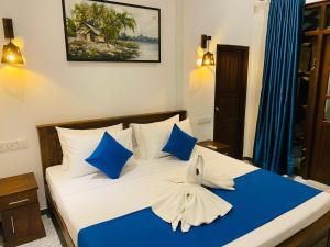 a bedroom with a bed with blue and white pillows at Little Villa in Habaraduwa