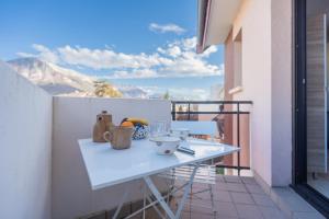 a white table on a balcony with a view of mountains at Cozy studio, very close to Lake Annecy in Annecy