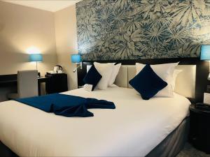 a bedroom with a large white bed with blue pillows at Best Western Allegro Nation in Paris