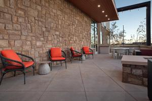 a patio with chairs and tables and a stone wall at Hilton Garden Inn Denver Airport Tower Road in Denver