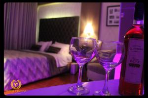 two wine glasses sitting on a table with a bottle of wine at Hotel Venecia in Huánuco