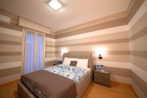 Dormitorio con paredes a rayas, cama y ventana en Sirmione4U - Domus by the Castle, en Sirmione