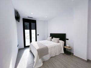a white bedroom with a white bed and a window at Adagio - Apartamentos La Clave in Pozoblanco