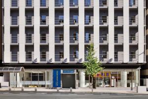 神户神户三宫优尼佐酒店的一栋白色建筑，前面有一棵树