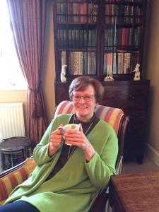 una mujer sentada en una silla sosteniendo un celular en Stoneborough House B&B en Budleigh Salterton