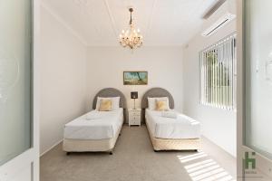 two beds in a white room with a chandelier at edgeware house in Sydney