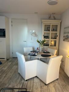 a living room with a table and white chairs at Le Normandy 5star in Cadzand