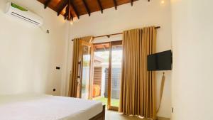 a bedroom with a bed and a sliding glass door at Villa Navodi in Negombo