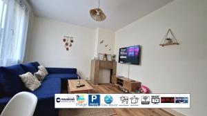 ein Wohnzimmer mit einem blauen Sofa und einem Fernseher in der Unterkunft Caprices des vagues - A 300 m de la plage et à 4 kilomètres de Nausicaa, Place de parking privée, Eau douce, Netflix, Primes Vidéo, Wifi haut débit in Le Portel