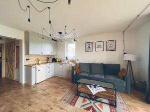 a living room with a couch and a kitchen at Apartamenty Skoczybruzda in Chmielno