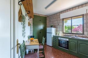 Una cocina con gabinetes verdes y una mesa y una ventana. en Casa Lola Preciosa azotea vistas panorámicas, en Almuñécar