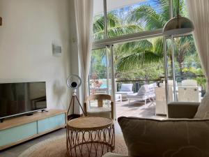 a living room with a tv and a couch and a table at sea beach pool in Bain Boeuf