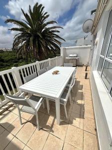 a white table and chairs on a patio with a palm tree at Riptide at no 14 in Sea Vista
