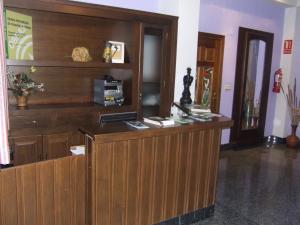vestíbulo con recepción de madera y estantería de libros en Hostal Rural El Padul, en El Padul