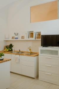 a kitchen with white cabinets and a flat screen tv at Casa Tua - Sea View Chianca in Vieste +27 photos